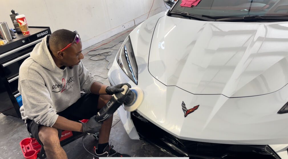 employee buffing a white sports car with toolbench in the background